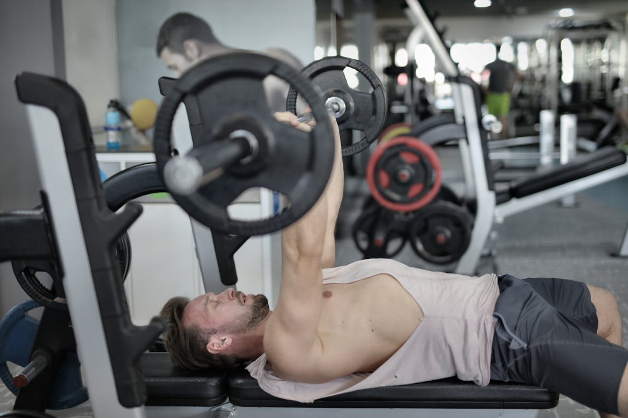 The Art of Drawing Readers In: Your attractive post title goes here A young man performs a bench press exercise with a barbell in a modern gym environment.